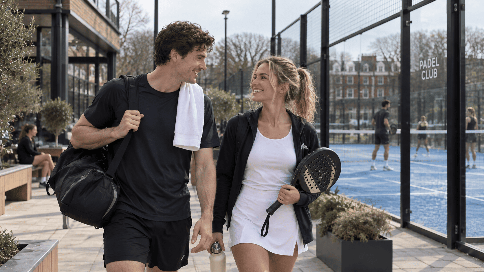 Couple arriving at a modern UK padel venue with a racket wrapped as a present